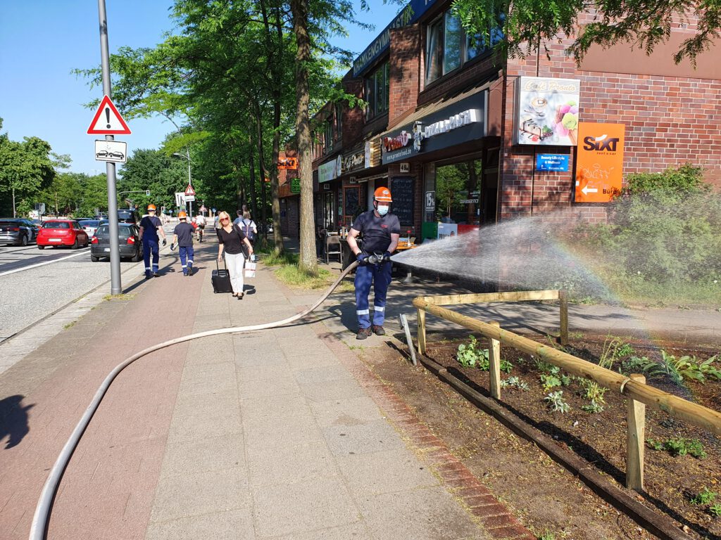 Feuerwehrmann bewässert das Beet